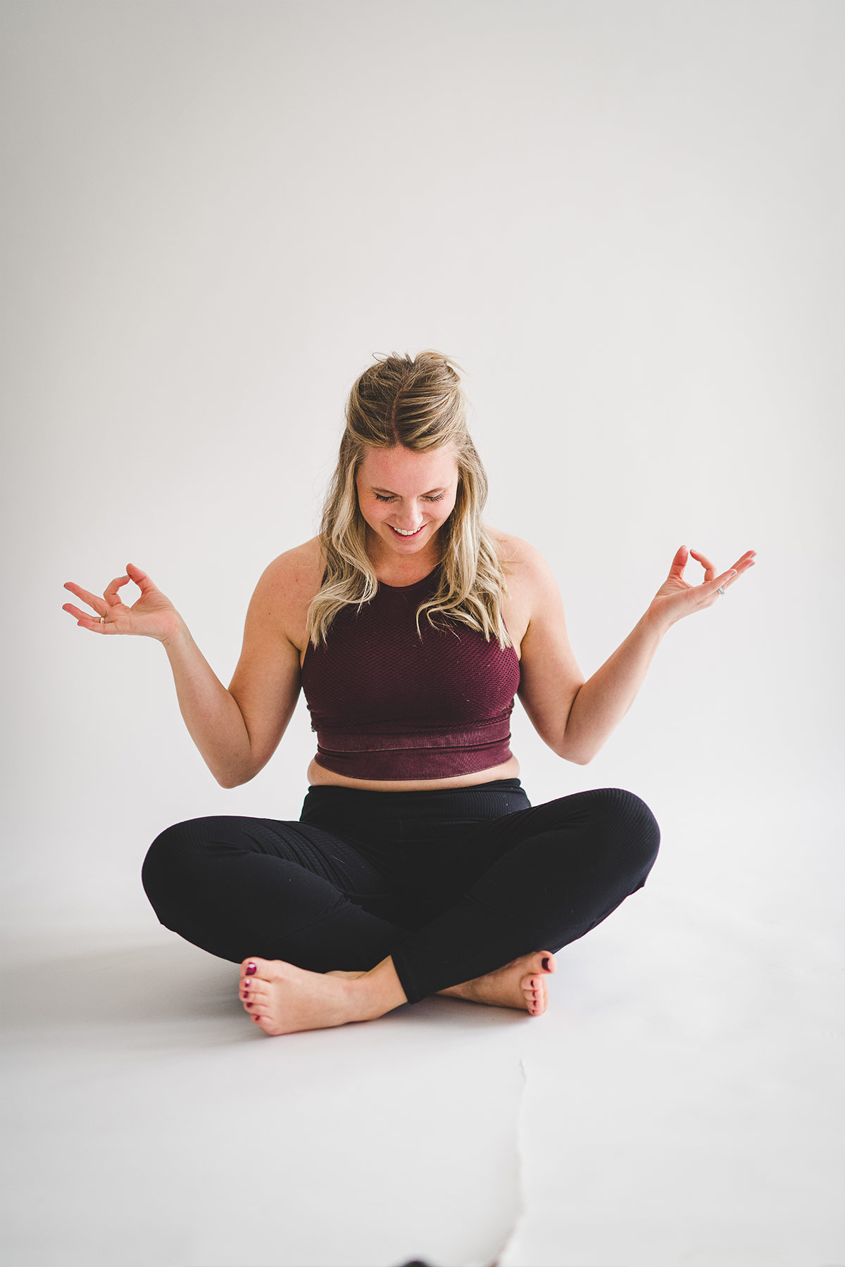 women in maroon shirt and black leggings practicing yoga