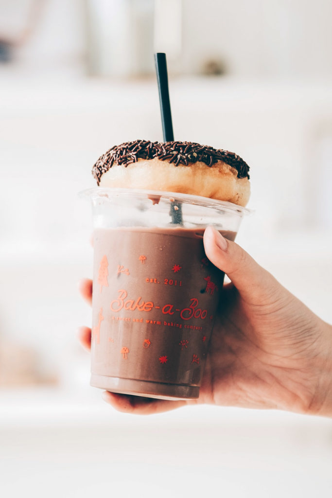 Cup of cold brew coffee with a donut sitting on lid
