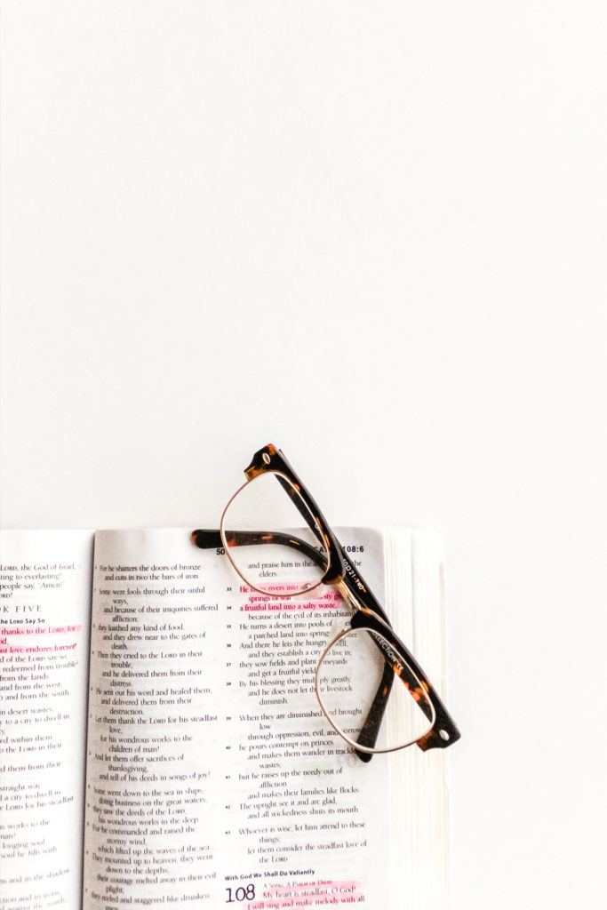Open bible with glasses on a white background