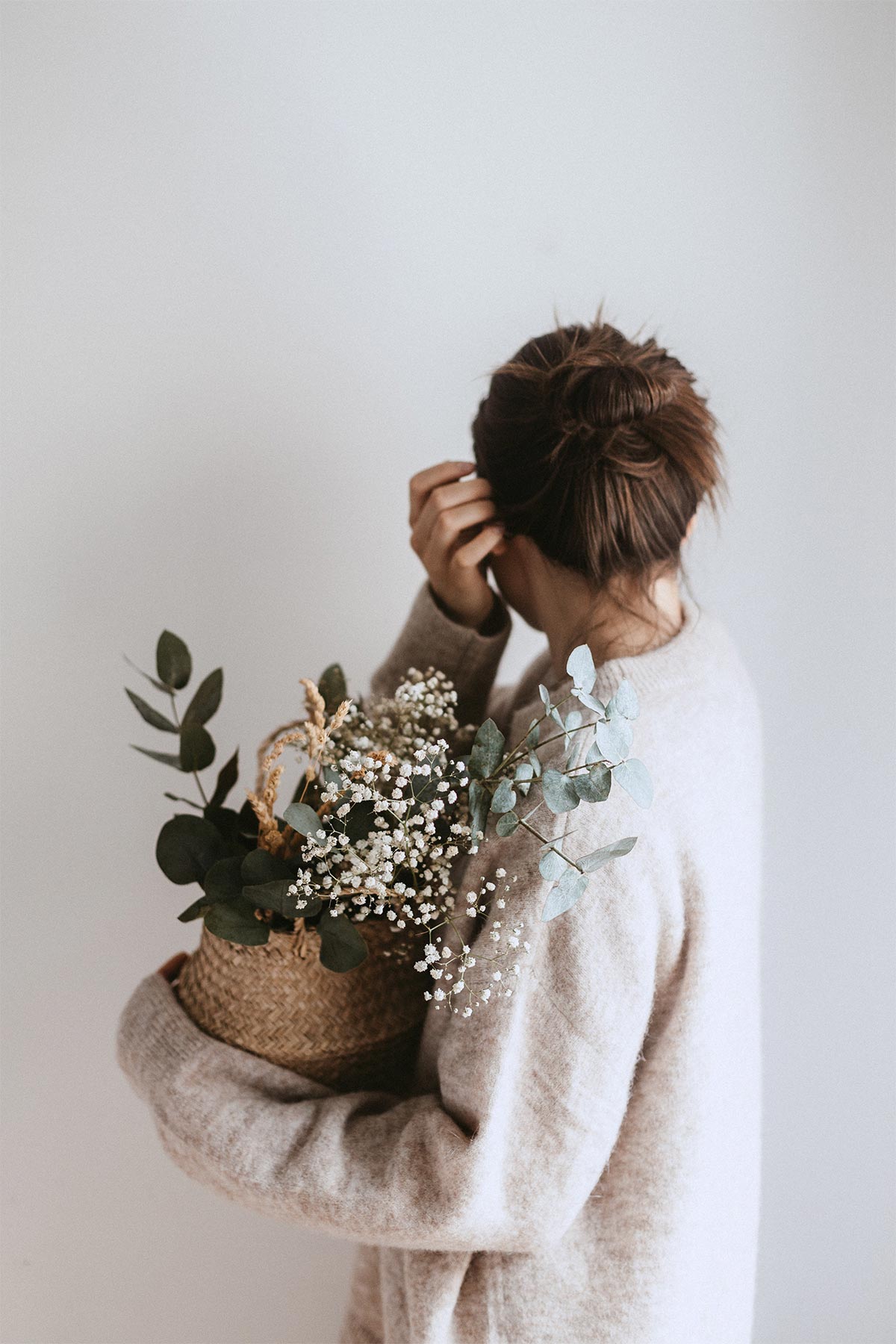 woman holding basket of greenery