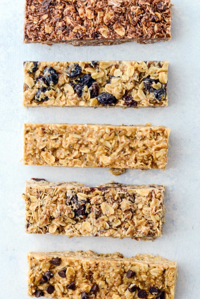 A mixture of different flavors of no-bake granola bars on a neutral background.