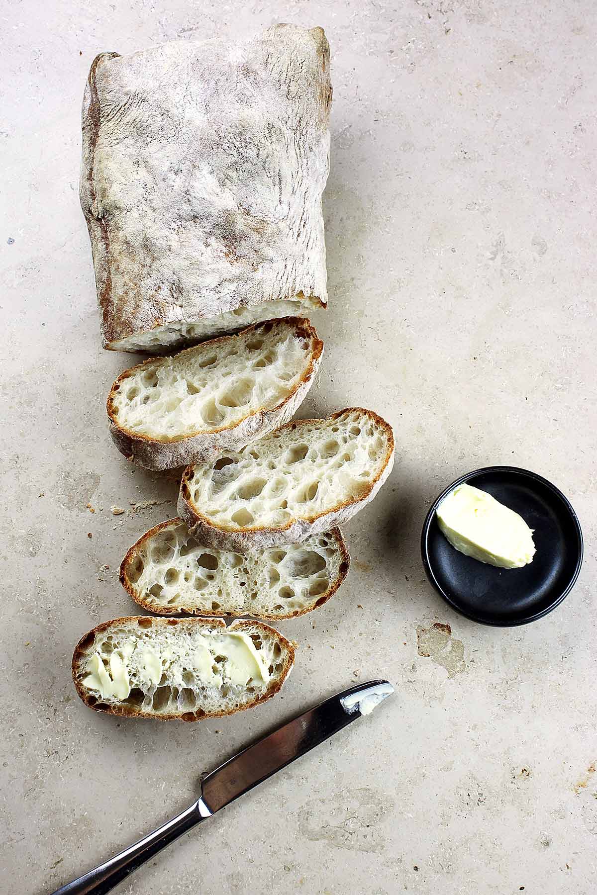 Loaf of bread sliced with knife and butter - carbohydrates