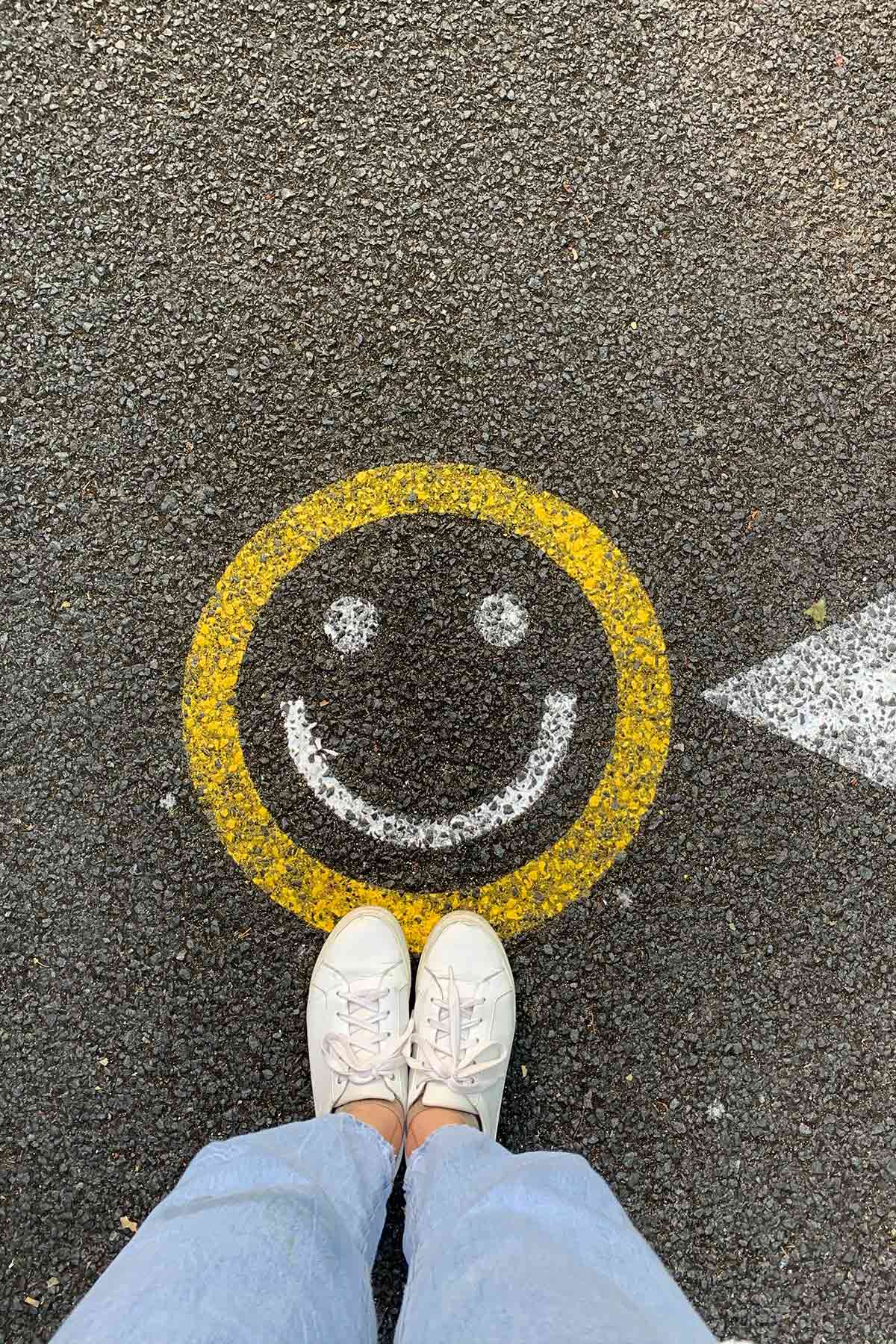 Painted smiley face on cement with white shoes