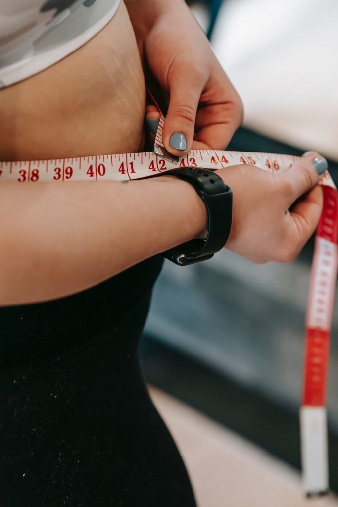 woman measuring waist with tape measure